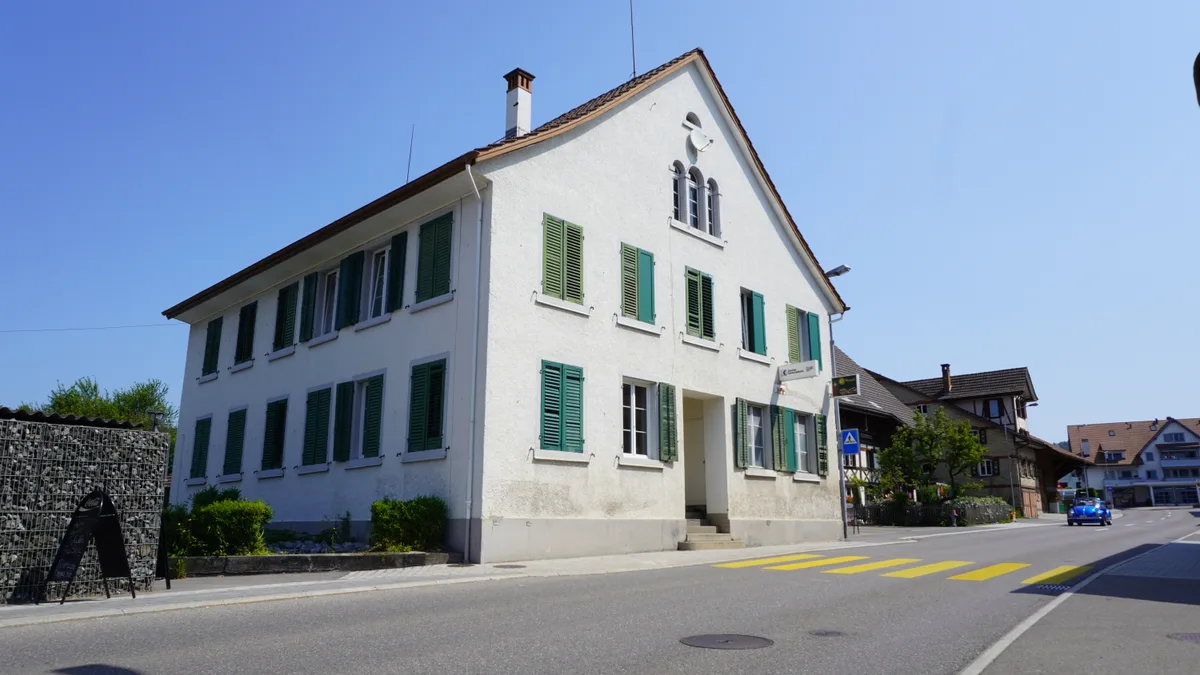 Ein Haus mit grünen Fensterläden an einem sonnigen Junitag.